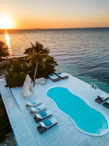 a pool with lounge chairs and the ocean at sunset at Quinta del Mar Sunset in Isla Mucura