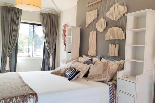 a bedroom with a white bed with pillows on it at Relaxar em Búzios Praia de Manguinhos 5 suítes in Búzios