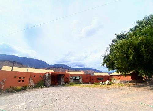 a dirt road in front of a building with mountains in the background at Finca La Candelaria in Maimará