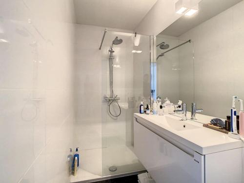 a white bathroom with a sink and a shower at Appartement 'Witte Berg' De Panne in De Panne