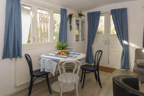 a dining room with a table and chairs and blue curtains at Gezellig ingerichte blokhut op een rustig park! in Putten