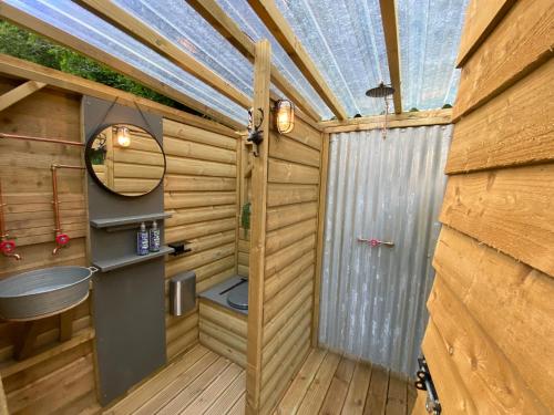 a wooden sauna with a mirror and a sink at Exclusive Use Riverside Landpods at Wildish Cornwall in Bodmin