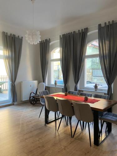 a dining room with a table and chairs and windows at Haus Felsenpost in Stadt Wehlen