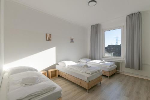 2 camas en una habitación con ventana en T&K Apartments-Duisburg 4 Zimmer Apartment, en Duisburg