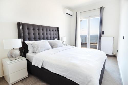 a white bedroom with a large bed and a window at Noir Luxury Suite by CorfuEscapes in Corfu