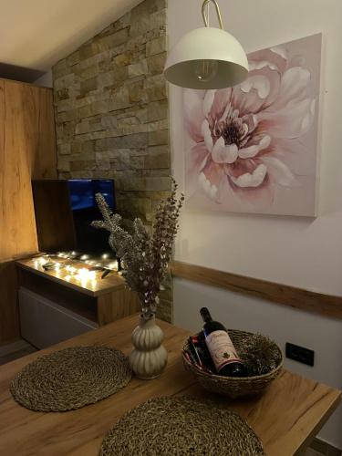 a table with a vase of flowers and a bottle of wine at Apartmani NLUX and SPA in Kopaonik