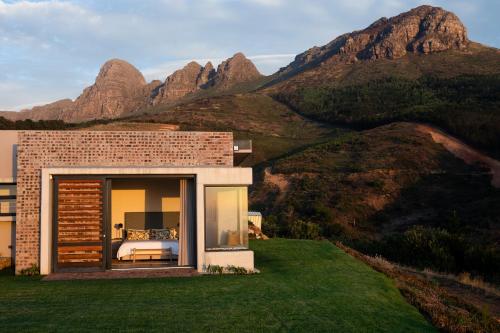 una casa en una colina con montañas en el fondo en Taaibosch Collection, en Stellenbosch