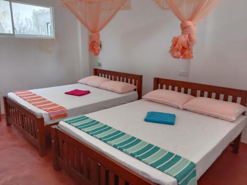 two beds sitting next to each other in a room at Happy Stay Holiday Inn in Hikkaduwa