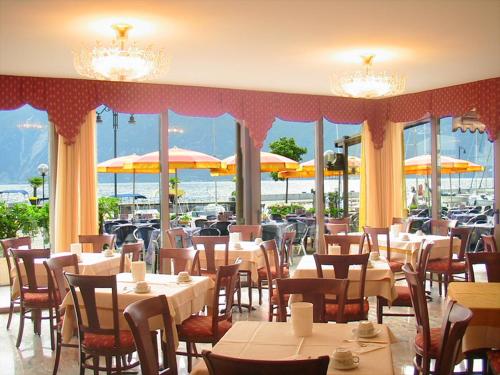 ein Restaurant mit Tischen, Stühlen und Sonnenschirmen in der Unterkunft Hotel Sole - Limone in Limone sul Garda