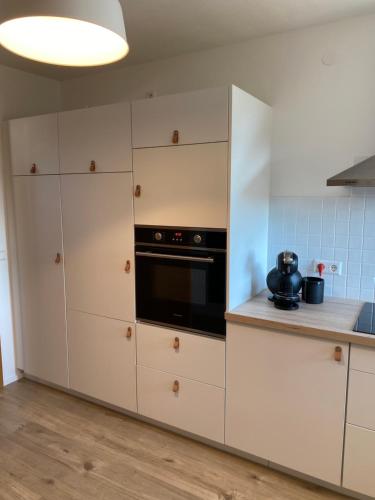 a kitchen with white cabinets and a black oven at Appartement Am Waldweg in Achern