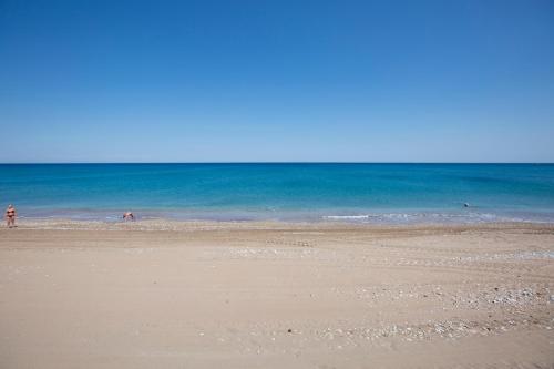 a beach with people swimming in the ocean at Serenity Sea-View Home in Afantou