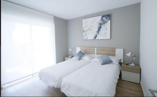1 dormitorio blanco con 1 cama blanca grande con almohadas azules en Lo Pagan Marina Center, en Lo Pagán