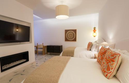 a hotel room with two beds and a flat screen tv at LOtel-Casa Arca in San Miguel de Allende