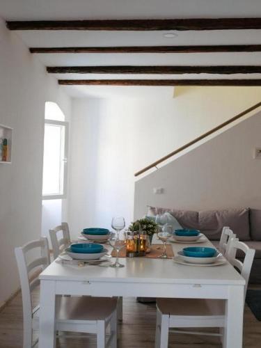 a white dining room table with plates and wine glasses at Apartments Blue Lavender in Cres