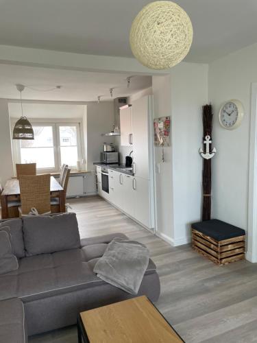 a living room with a gray couch and a kitchen at Wohnungen mit direktem Meerblick in Laboe