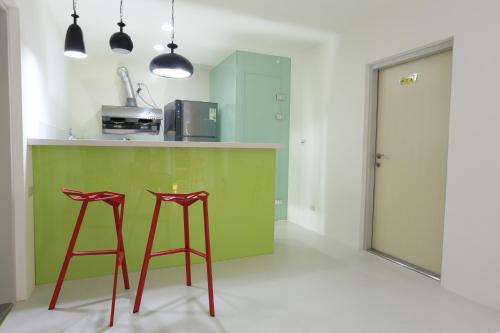 una cocina con dos taburetes rojos en un mostrador verde en Ocean Sky Homestay en Toucheng