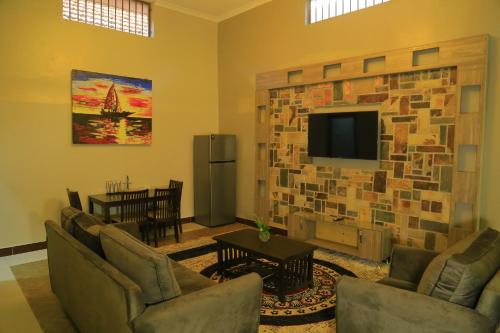 a living room with a stone wall with a flat screen tv at Royal Victoria House in Kampala