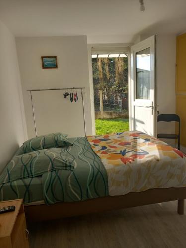 um quarto com uma cama e uma porta de vidro deslizante em La Menuiserie em Myennes
