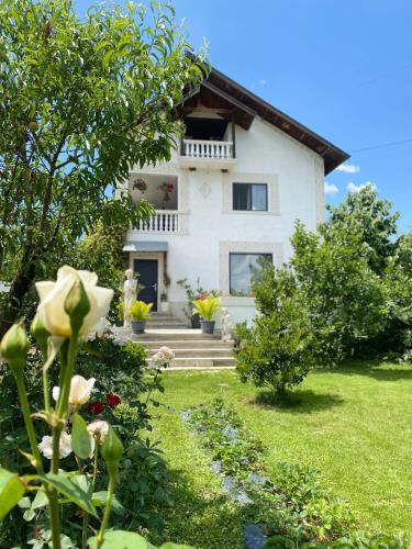 a white house with stairs and flowers in front of it at Craita Merelor The PLACE in Aninoşani