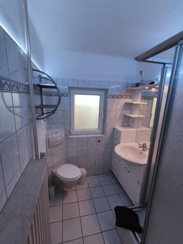 a white bathroom with a toilet and a sink at Lütt Nest Föhr in Alkersum