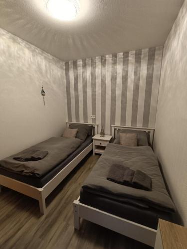 sypialnia z 2 łóżkami i ścianą z paskami w obiekcie Lütt Nest Föhr w mieście Alkersum