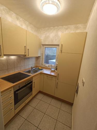 uma cozinha com armários brancos, um lavatório e uma janela em Lütt Nest Föhr em Alkersum