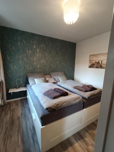 2 Betten in einem Schlafzimmer mit grüner Wand in der Unterkunft Lütt Nest Föhr in Alkersum