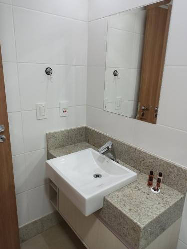 a bathroom with a white sink and a mirror at Flat Pedra Azul in Aracê