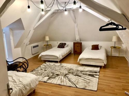 a attic room with two beds and a rug at La Closerie - trois chambres in Vicq-sur-Gartempe