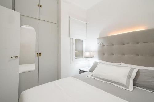 a white bedroom with a white bed and a mirror at Near FCB STADIUM. One car free parking. in Barcelona