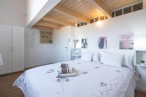 biała sypialnia z dużym białym łóżkiem z kwiatami w obiekcie Porta Galliera Apartment w Bolonii