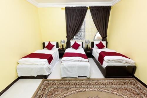 a bedroom with two beds with red pillows and a window at Al Eairy Apartments - Al Madinah 09 in Medina