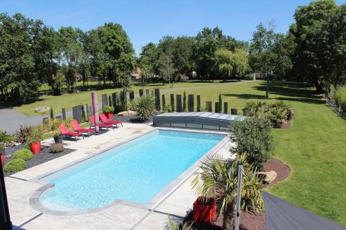 a swimming pool in a yard with chairs and trees at Villa grand standing avec piscine proche Nantes in La Chapelle-Heulin