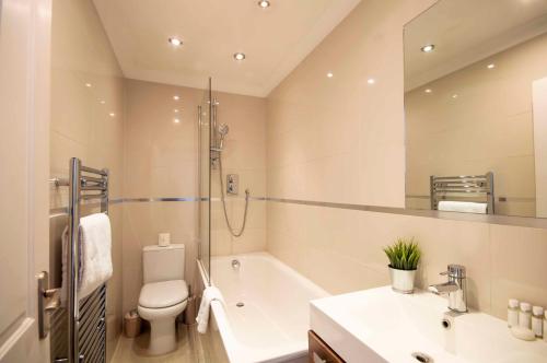 e bagno con vasca, servizi igienici e lavandino. di Kensington - Lexham Gardens by Viridian Apartments a Londra