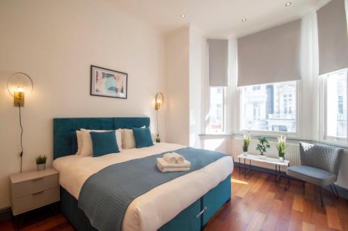 una camera con un grande letto con testiera blu di Kensington - Lexham Gardens by Viridian Apartments a Londra