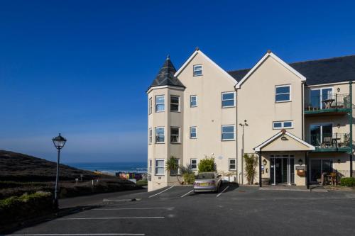 a large building with a car parked in a parking lot at Beachcombers Apartments in Newquay