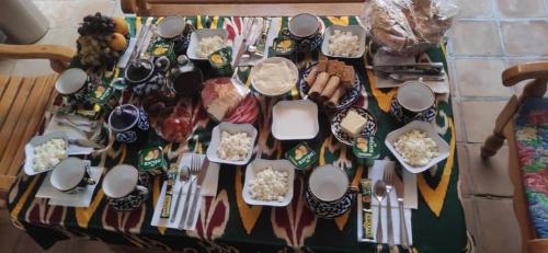 einen Tisch voller Geschirr und Speisen auf dem Tisch in der Unterkunft Aist House in Buxoro