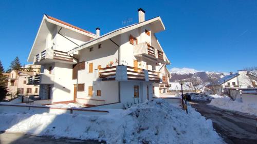 un grande edificio bianco con la neve intorno di Appartamento Bucaneve a Ovindoli