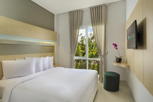 a bedroom with a large white bed and a window at Zizz Convention Hotel in Denpasar