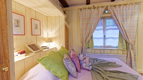 a bedroom with a bed with pillows and a window at Remparts de Riquewihr - Refuge du Lutin - Studio in Riquewihr