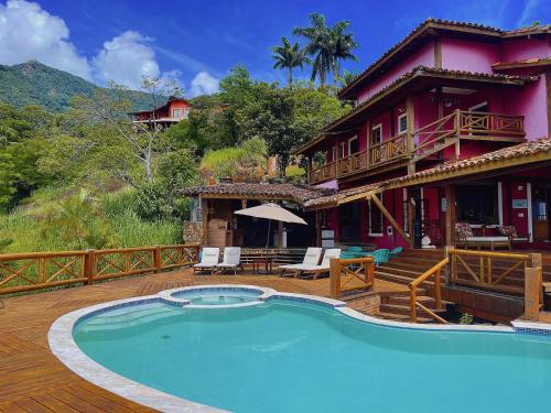 a house with a swimming pool in front of a house at Mooi Guest House in Ilhabela