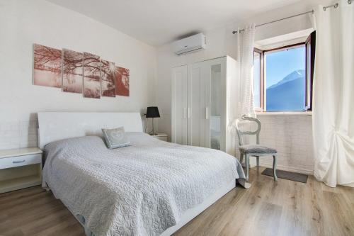 a white bedroom with a bed and a window at Casa sul Lago di Como in Pianello Del Lario