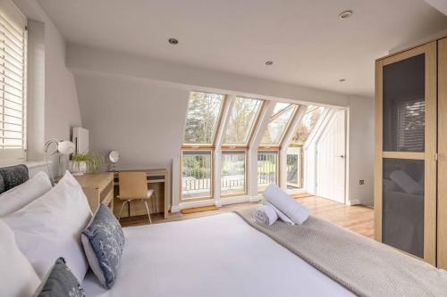 a bedroom with a large white bed and windows at Cosy Home Near Sunningdale/Ascot/Wentworth Golf Club in Sunninghill