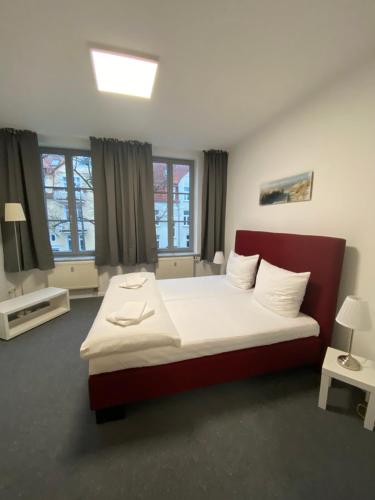 een slaapkamer met een bed en 2 ramen bij Pension Villa Ostseetraum in Warnemünde