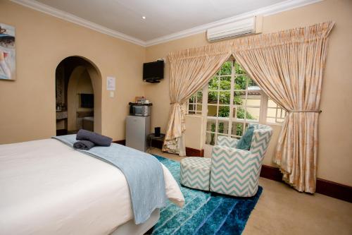 a bedroom with a bed and a chair and a window at TDM's Boutique Guest House in Pretoria