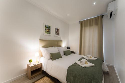 um quarto com uma grande cama branca com um cobertor verde em Casa Trindade no Porto