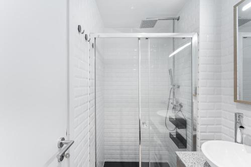 um banheiro branco com chuveiro e pia em Casa Trindade no Porto