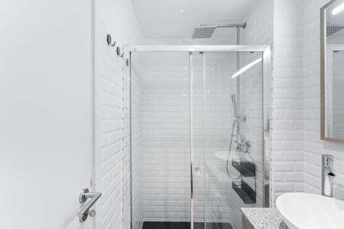a white bathroom with a shower and a sink at Casa Trindade in Porto