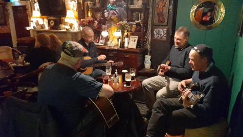 un grupo de hombres sentados en un bar tocando instrumentos en The Yoke en Ballybrittas