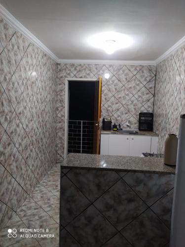 a kitchen with a counter in a room with tiles at Apartamento no centro de Vicosa-ce in Viçosa do Ceará